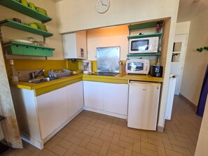 Eine kompakte Küche mit Spüle, Mikrowelle, Toaster und Kühlschrank.