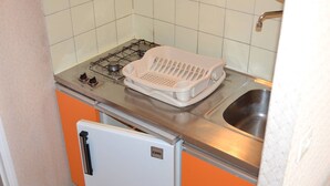 Una cucina compatta con piano cottura a gas, lavello bianco e piccolo frigorifero.