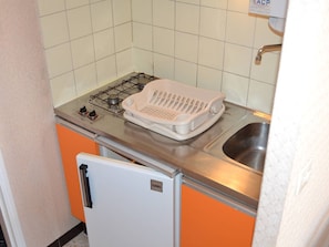 A compact kitchen with a gas stove, a white sink, and a small refrigerator. - Studio for 2 guests near beach - Cap d'Agde (Cap d'Agde)