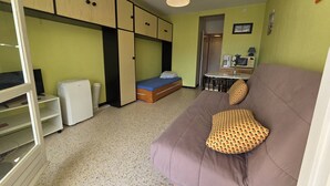 A compact room with a bed, a sofa, a kitchenette, and a small table. - Studio in Cap d'Agde, AC - 4 guests, near beach (Cap d'Agde)