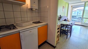 A compact kitchen with a gas stove, sink, and a compact refrigerator. - Studio in Cap d'Agde, AC - 4 guests, near beach (Cap d'Agde)