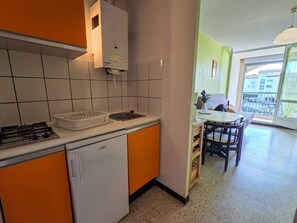 Eine kleine Küche mit Gaskochfeld, Spüle und einem kompakten Kühlschrank.