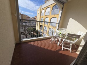 Ein Balkon mit Tisch und Stühlen, Blick auf Gebäude und einer Brüstung.
