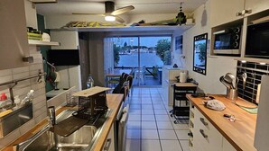 Una cocina moderna con vista al mar, un comedor con sillas y una pequeña mesa con utensilios de cocina.