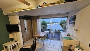 Habitación compacta con una mesa de comedor, sillas, un televisor pequeño y vista al agua.