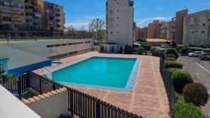 Una piscina rodeada de muros de ladrillo, con un edificio alto al fondo.
