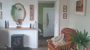 A living room with a wooden chair, a small table, a mirror, and a door leading to another room. - House Sleeps 2 With Garden and Parking (Dublin)