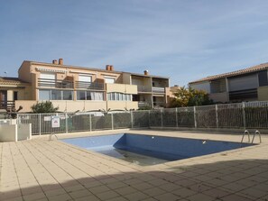 A residential building with a swimming pool, a gated entrance, and a clear sky. - Apartment near naturist area - 6 guests (Cap d'Agde)