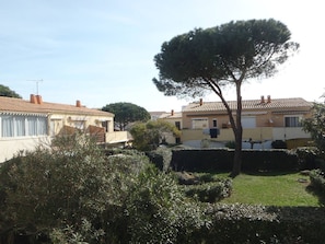 A residential area with houses, a large tree, and a well-maintained lawn. - Apartment near naturist area - 6 guests (Cap d'Agde)