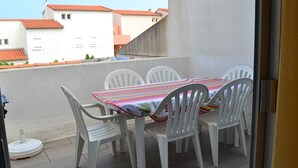 A balcony with a table and chairs, a view of buildings with red roofs, and a clear sky. - Quiet apartment with parking - 6 guests (Cap d'Agde)