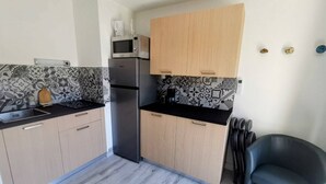 Cozinha compacta com micro-ondas, frigorífico e armários de madeira.