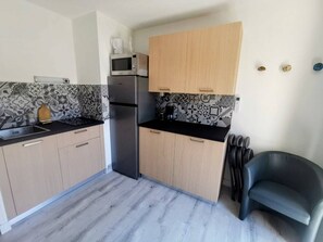 Eine kleine Küche mit Mikrowelle, Kühlschrank und Holzschränken.