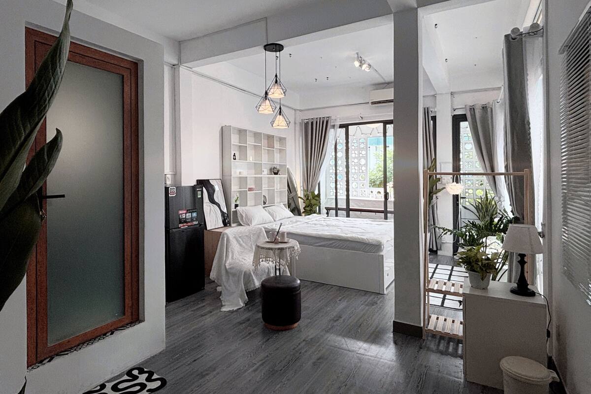 A modern bedroom with a bed, bedside tables, a wardrobe, and a large window.