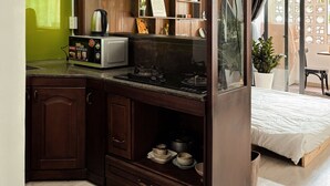 A kitchen with a stove, microwave, and cabinets. - Àla Homestay District 10 Apartment (Ho Chi Minh City)