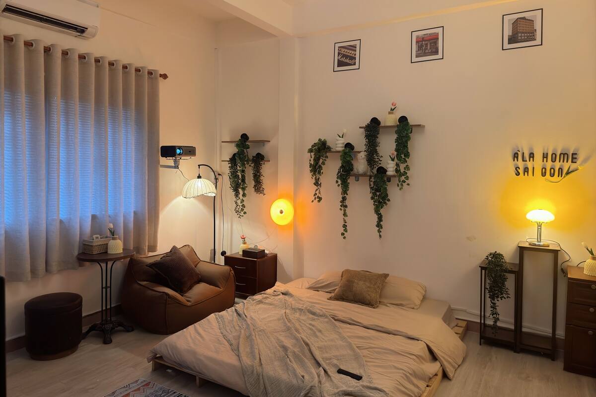 A modern bedroom with a bed, a desk, a chair, a lamp, and wall-mounted plants.