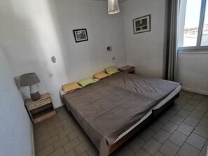 Ein Schlafzimmer mit einem Bett, Nachttischen, einer Lampe und zwei gerahmten Bildern an der Wand.