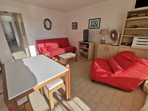 Ein Wohnzimmer mit einem roten Sofa, einem weißen Tisch und einer TV-Konsole.