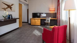A hotel room with a desk, chair, TV, lamp, and a red chair. - 2 Person Holiday Park Home in Neu-isenburg (Neu-Isenburg)