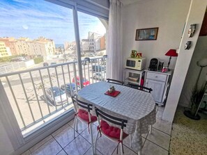 Ein Balkon mit Tisch und Stühlen, einer Küchenzeile und Blick auf die Stadtlandschaft.