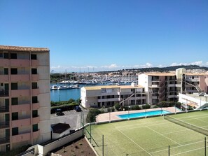 Ein Wohngebiet mit Tennisplatz, Schwimmbad und einem Yachthafen im Hintergrund.