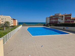 Ein Schwimmbecken mit Blick auf das Meer, umgeben von Gebäuden.