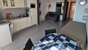 A compact living space with a kitchenette, a sofa, a dining area, and a bed. - Studio with AC, sea view - 4 guests (Cap d'Agde)