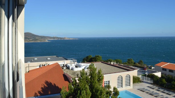 Un hotel frente al mar con vistas, piscina y aparcamiento.