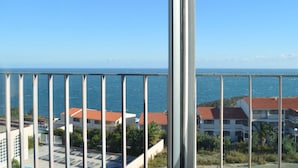 Un balcón con vista al mar y edificios de techos rojos.