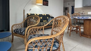 Un espacio de estar con un sofá, dos sillones, una mesa de comedor y una lámpara.