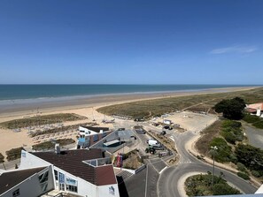 Eine Küstenlandschaft mit einer sich an einem Strand entlang schlängelnden Straße, einem Parkplatz und Gebäuden mit Beschilderung.
