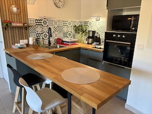 Een moderne keuken met een houten aanrecht, twee stoelen, een spoelbak, een magnetron en een oven.