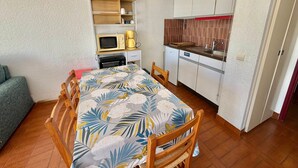 Ein kleines Zimmer mit einem Bett, einer Kochnische, einer Mikrowelle, einer Kaffeemaschine und einem Sessel.