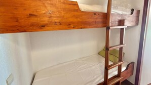 Ein Etagenbett mit Holzrahmen und einer Leiter, eine weiße Matratze und eine Plastiktüte im oberen Bett.