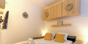 Ein Hotelzimmer mit einem Bett, zwei Kissen, einem Wandregal und einer Wanduhr.