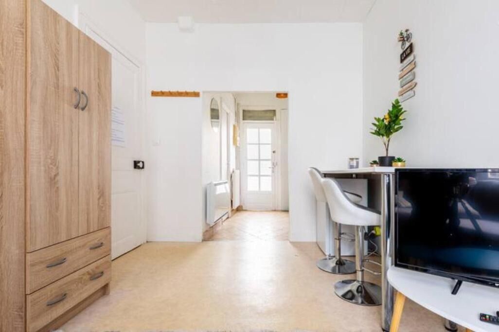 Une cuisine moderne avec des meubles en bois, un téléviseur et un coin bar équipé de tabourets.