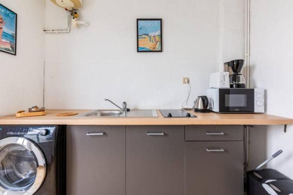 A compact kitchen with a washing machine, a sink, a microwave, and a coffee maker.