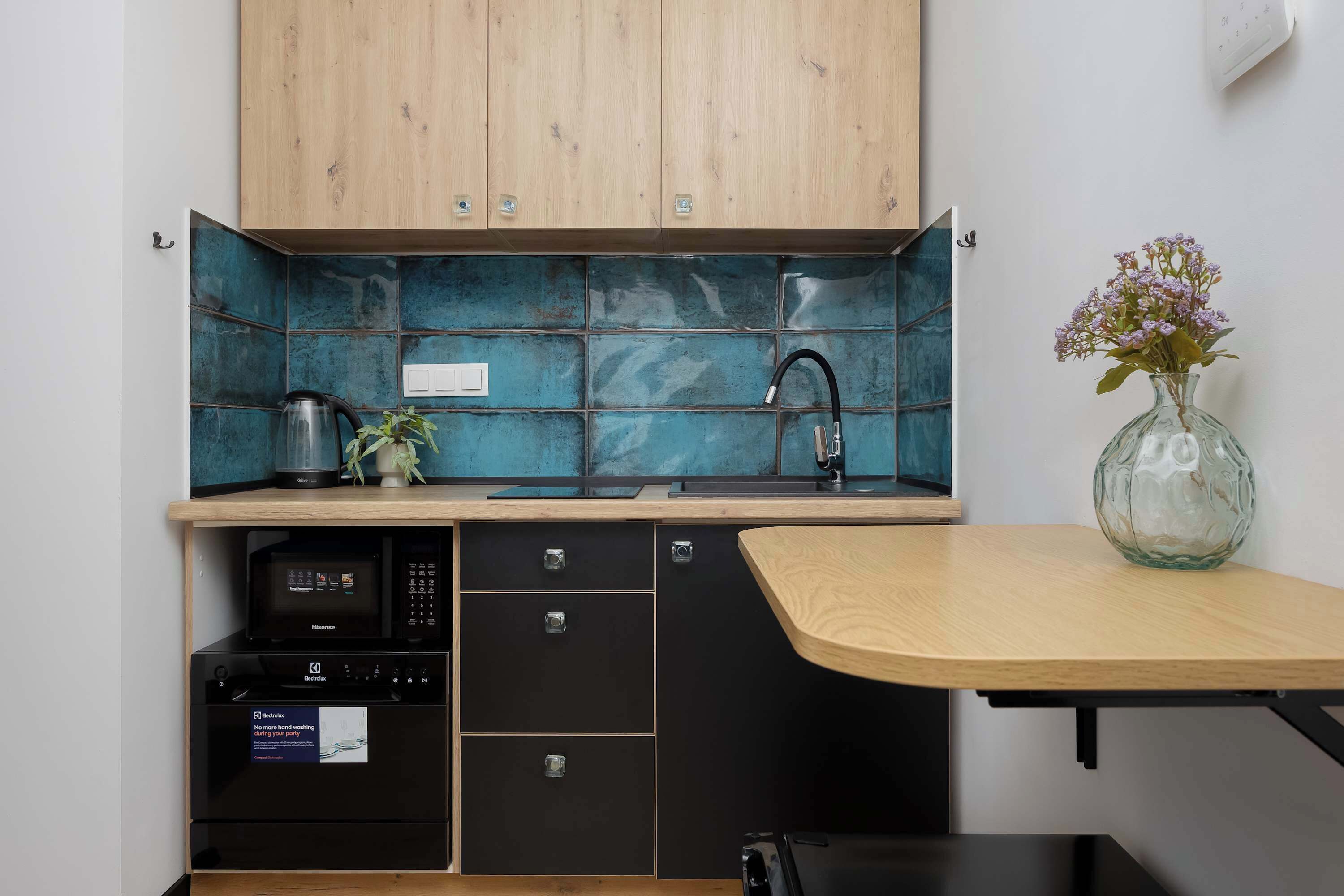 Une cuisine compacte avec des meubles en bois, un crédence en carreaux bleus et un petit plan de travail.