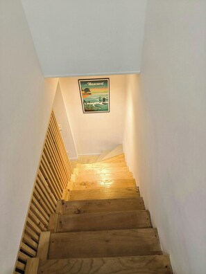 A wooden staircase with a picture of a beach scene on the wall. - Stone house on the banks of the Dordogne (Arveyres)