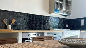 Una cucina moderna con un tavolo di legno, zoccolo a mosaico nero e elettrodomestici in acciaio inossidabile.