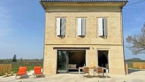 Un edificio a due piani con tetto piatto, ampie finestre e un patio arredato.