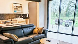 Un soggiorno moderno con un divano, un tavolino da caffè e vista sull'esterno attraverso ampie finestre.