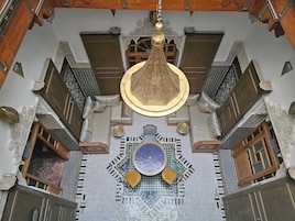 Um quarto com chão de azulejos estampados, um candeeiro suspenso e um objeto decorativo na parede.