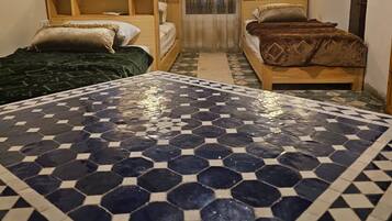 Una habitación con dos camas, piso estampado y una ventana con cortinas.