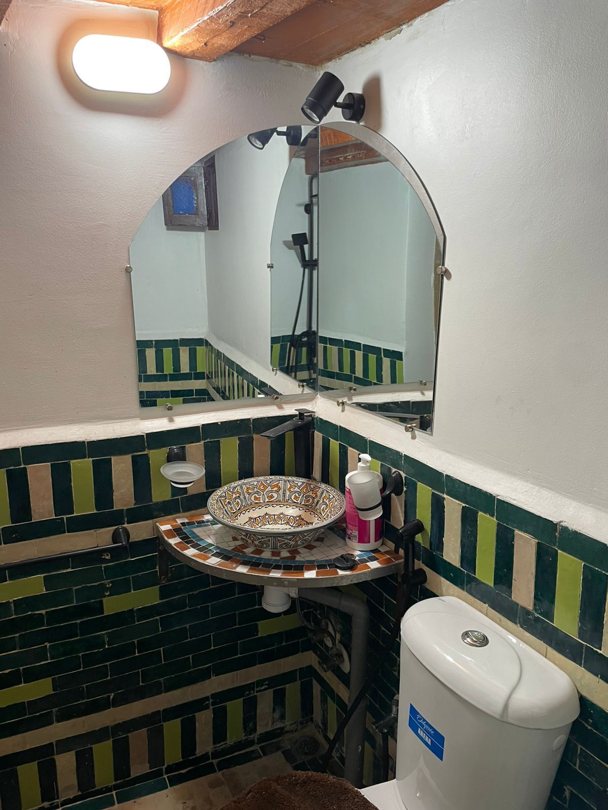 Un baño con piso de baldosas, un lavabo con un recipiente decorativo, un inodoro y un espejo con una lámpara.