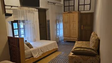 Ein Zimmer mit einem Bett, einem Schlafsofa, einem Kleiderschrank und einem Deckenventilator.