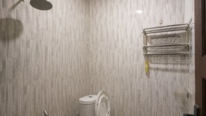 A bathroom with a shower, toilet, and a towel rack. - Puri Kawan Guesthouse (Denpasar)