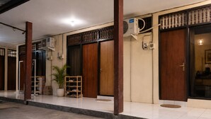 A building with a tiled entrance, wooden doors, and a potted plant. - Puri Kawan Guesthouse (Denpasar)