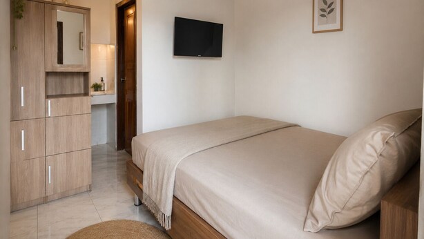 A bedroom with a bed, a TV, a wardrobe, and a mirror. - Puri Kawan Guesthouse (Denpasar)