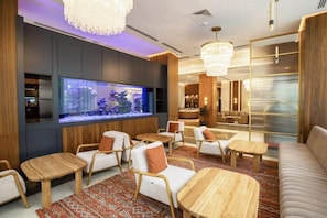 A modern lounge area with seating, a large aquarium, and ambient lighting. - Zumma Hotel (Almaty)