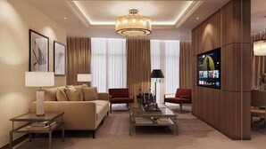 Uma sala de estar moderna com sofá, duas poltronas, mesa de centro, televisão e lustre.